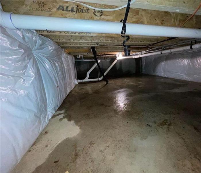 Crawlspace with encapsulation and minor water on the concrete substrate