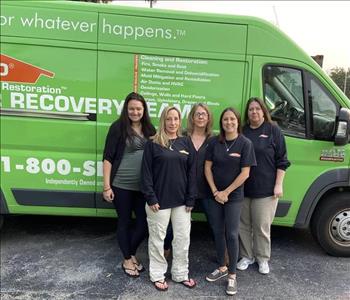 5 girls wearing SERVPRO uniforms standing in front of van