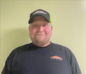 Man standing against a green wall with a Servpro shirt on