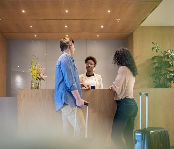 Hotel Front Desk.  Man and woman talking to agent behind desk