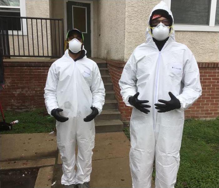 Two technicians in PPE outside of a home