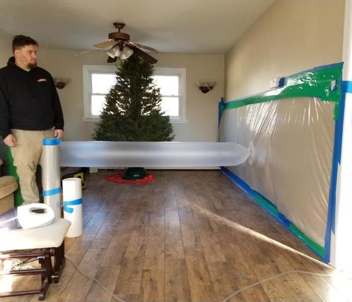 Technician drying a water damaged room with isolation drying